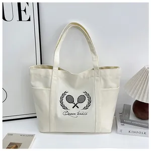 Detail of canvas tote bag showing tennis racket print, side pocket, and reinforced stitching