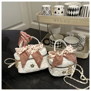 Macro detail of white quilted mini bag with gold flower hardware and floral scarf