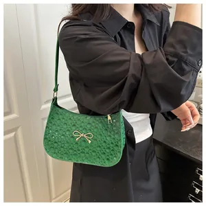 Detail of green embossed leather underarm bag with elegant gold bow metal buckle