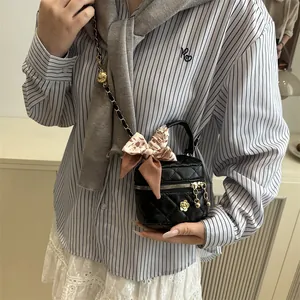 Mini black quilted chain bag with camellia flower detail and silk scarf handle