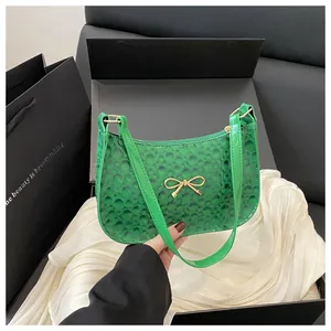 Detailed shot of green patent leather bag with gold bow and premium gift packaging