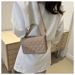 Close-up of khaki quilted crossbody bag with gold metal trim worn by model