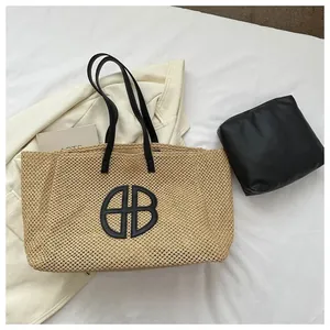 Détail du sac cabas en paille tissée avec logo rond noir et pochette intérieure assortie