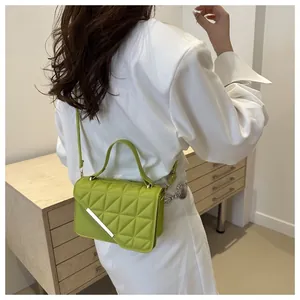 Side view of a lime green quilted handbag with a silver metal bar and crossbody strap