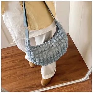 Detailed view of light blue puffer half-moon bag with pleated texture and soft strap