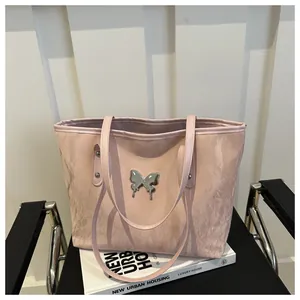 Dettaglio borsa tote rosa chiaro con emblema farfalla argento su sedia design