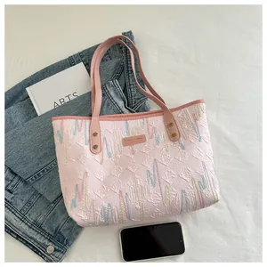 Detail of pink tote bag with diamond texture, colorful embroidery and CAHRES & HEKA logo