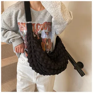 Close-up of black bubble textured crossbody tote bag worn by a model on a urban background