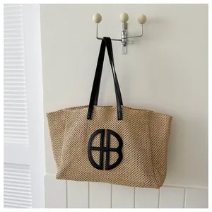 Woven straw tote bag with black HB lettering and leather shoulder straps