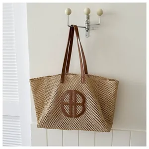 Straw woven tote bag with brown leather handles and circular logo detail