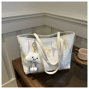 Close-up of textured white tote bag with colorful striped embroidery and cloud charm