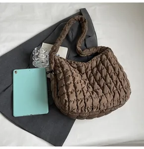 Detail of a brown quilted bubble tote bag showing soft texture and padded nylon fabric