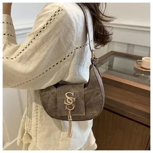 Close-up of vintage crescent moon bag featuring golden metal letters and tassel detail