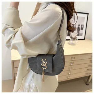 Close-up of a dark grey crescent bag with a gold S-logo and metallic tassel detail