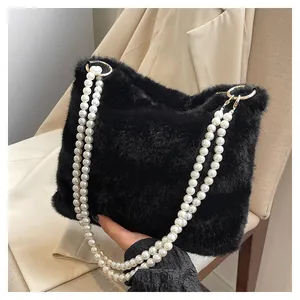 Gros plan d'un sac en fausse fourrure noire avec bandoulière perles et anneaux dorés