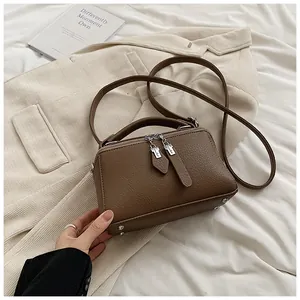 Detail of a brown lychee pattern Boston bag with silver hardware and a long strap