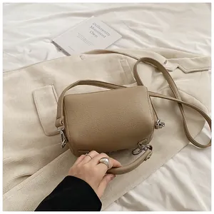 Detailed texture of khaki pebbled leather Boston bag on beige blazer background