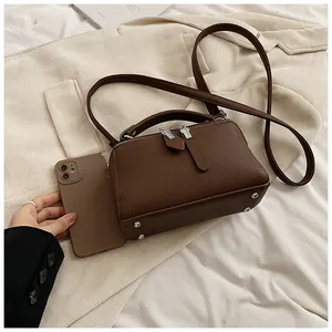 Detail of dark brown pebble leather Boston bag with metal zipper and phone for size reference
