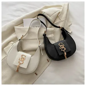 Detail of crescent moon bags in black and beige with gold logo and tassel accent
