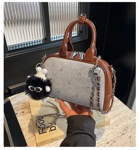 Detalle de bolso plateado brillante con ribete de charol marrón y remaches decorativos