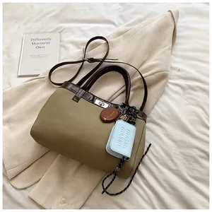 Flat lay of an olive green tote bag with rich charms on a soft linen background