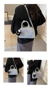 Detalle de bolso plateado con purpurina, cadena metálica y colgante de peluche negro
