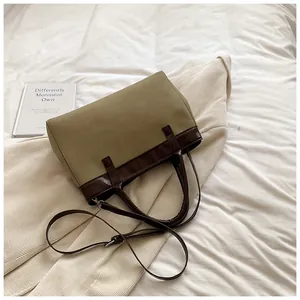Detail of olive green contrast tote bag with brown leather straps on soft fabric