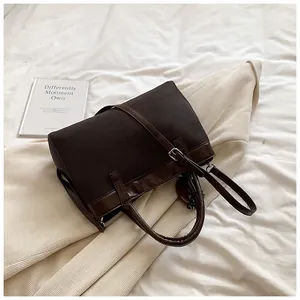 Detailed top view of large dark brown canvas tote bag with leather trim on white fabric