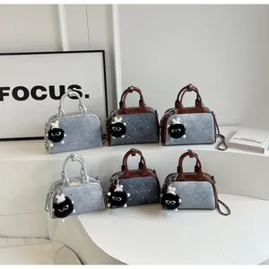 Detalle de bolsos bandolera de mezclilla con remaches metálicos, cadenas y dijes de felpa