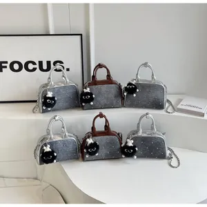 Detalle de bolsos cruzados de mezclilla con remaches plateados, cadenas y colgantes de felpa