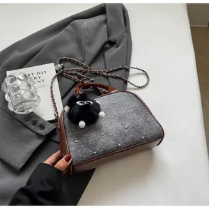Detalle de bolso acolchado gris con remaches plateados y colgante de monstruo