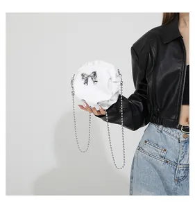 Détail du petit sac rond blanc plissé avec nœud argenté et bandoulière perles