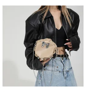 Détail du sac nuage plissé beige avec nœud argenté et bandoulière en chaîne perlée