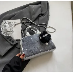 Detalle de bolso vaquero acolchado gris plata con tachuelas, cadena y colgante de peluche