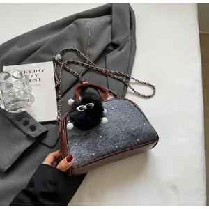 Detalle de bolso vaquero acolchado con perlas, ribetes de piel sintética y amuleto