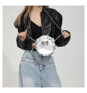 Détail d'un sac fleur 3D argenté avec noeud métallique et bandoulière perles