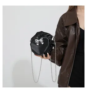 Détail du mini sac plissé noir avec nœud argenté et bandoulière en chaîne billes