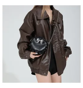 Détail du sac bandoulière rond noir plissé avec un nœud en métal argenté et une bandoulière