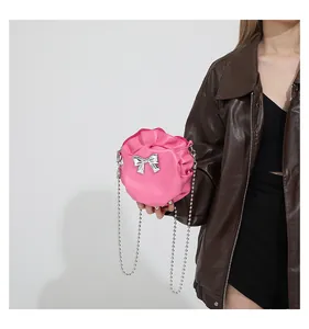 Détail du sac rond plissé rose avec nœud argenté et bandoulière en chaîne de perles