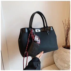 Black large tote bag in matte finish with leather trim and decorative charms