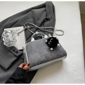 Detalle de bolso bandolera de mezclilla gris con ribete plateado y colgante peluche