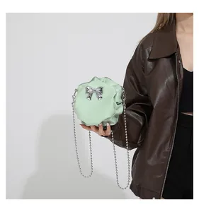 Détail d'un sac boule plissé vert menthe avec nœud argenté et bandoulière perlée