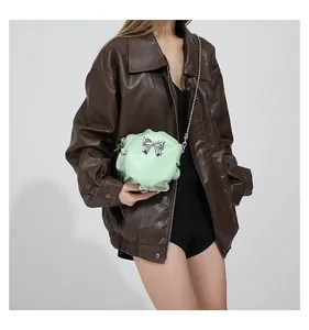 Gros plan du sac bandoulière plissé vert clair avec nœud argenté et bandoulière chaîne