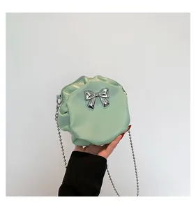 Détail du sac rond vert menthe avec nœud argenté et bandoulière en chaîne perle
