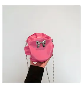 Détail d'un petit sac rond rose plissé avec nœud métallique argenté et bandoulière