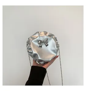 Détail du sac rond plissé argenté avec nœud métallique et bandoulière chaîne