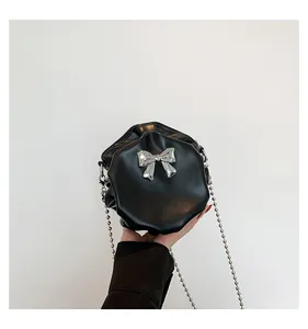 Détail du sac bandoulière plissé noir avec nœud argenté et fine bandoulière en chaîne