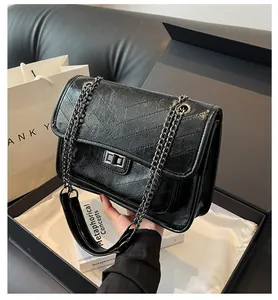 Détail du sac à chaîne noir avec texture matelassée en V et fermoir rotatif argenté en coffret