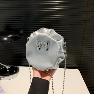 Sac bandoulière rond argenté métallisé avec plis, nœud et fine chaîne élégante