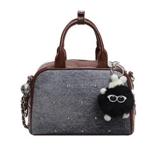 Bolso bandolera de mezclilla y cuero marrón con remaches y colgante de peluche negro